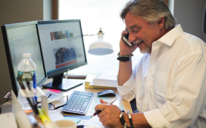 Dr. Charles Guglin, MD FACS on his phone at his desk.